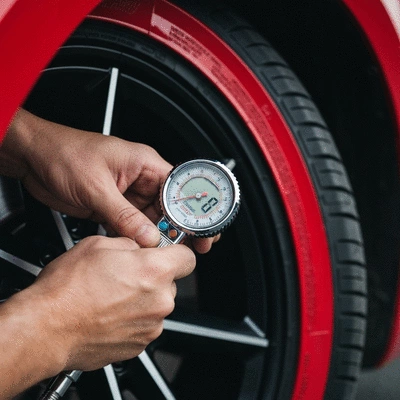 Hand checking car tire pressure with a gauge