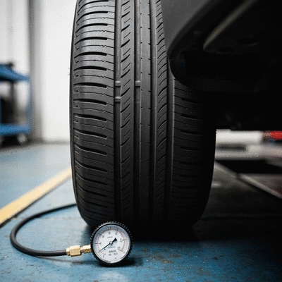 Car tire with good tread and pressure gauge on a workshop floor