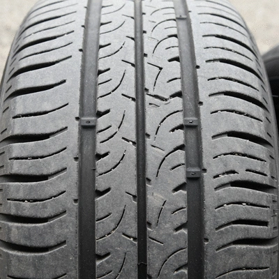 Close-up of a used car tire showing visible wear and tear on the tread, highlighting potential dangers, no text, no words, no typography, clean image