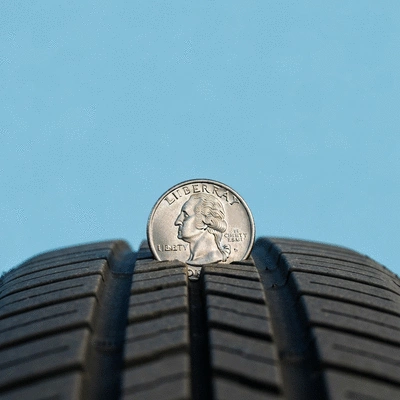 Gros plan d'une pièce de monnaie utilisée pour mesurer la profondeur de sculpture d'un pneu